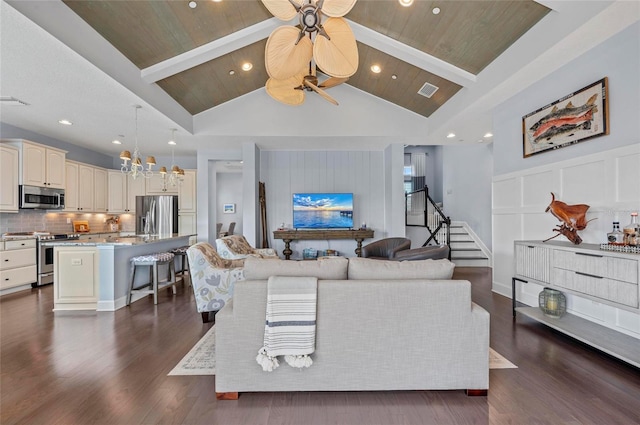 living area with beam ceiling, ceiling fan with notable chandelier, a decorative wall, wood ceiling, and dark wood-style flooring