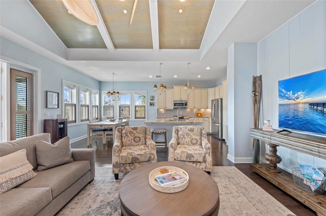 living area featuring beam ceiling, wood finished floors, recessed lighting, baseboards, and a chandelier