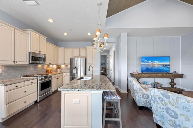 kitchen featuring cream cabinetry, stainless steel appliances, decorative backsplash, and a sink