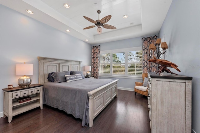 bedroom with a raised ceiling, recessed lighting, baseboards, and dark wood-style flooring