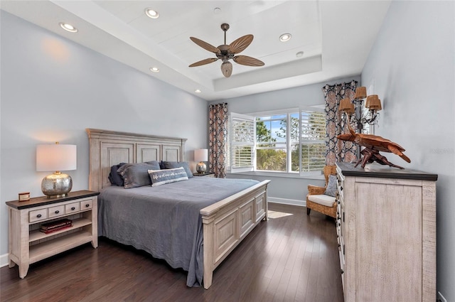 bedroom with baseboards, dark wood finished floors, recessed lighting, ceiling fan, and a raised ceiling