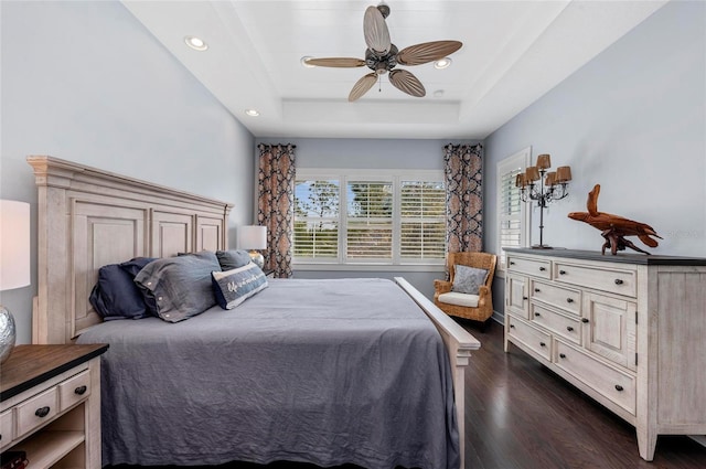 bedroom with a tray ceiling, recessed lighting, dark wood-style flooring, and ceiling fan