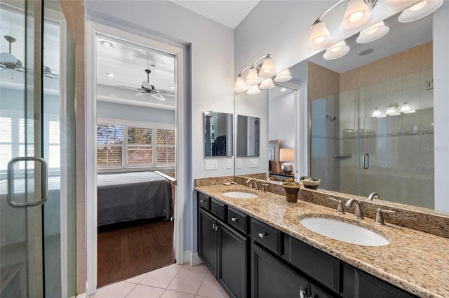 ensuite bathroom with a stall shower, ceiling fan, tile patterned flooring, a sink, and ensuite bathroom