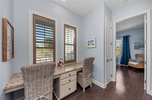 office with dark wood-style floors, built in desk, and baseboards