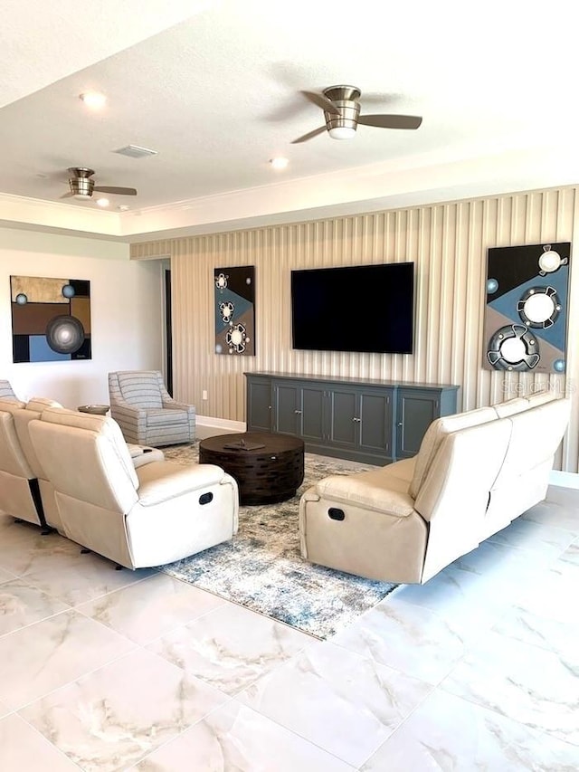 living area featuring visible vents, marble finish floor, a raised ceiling, and a ceiling fan