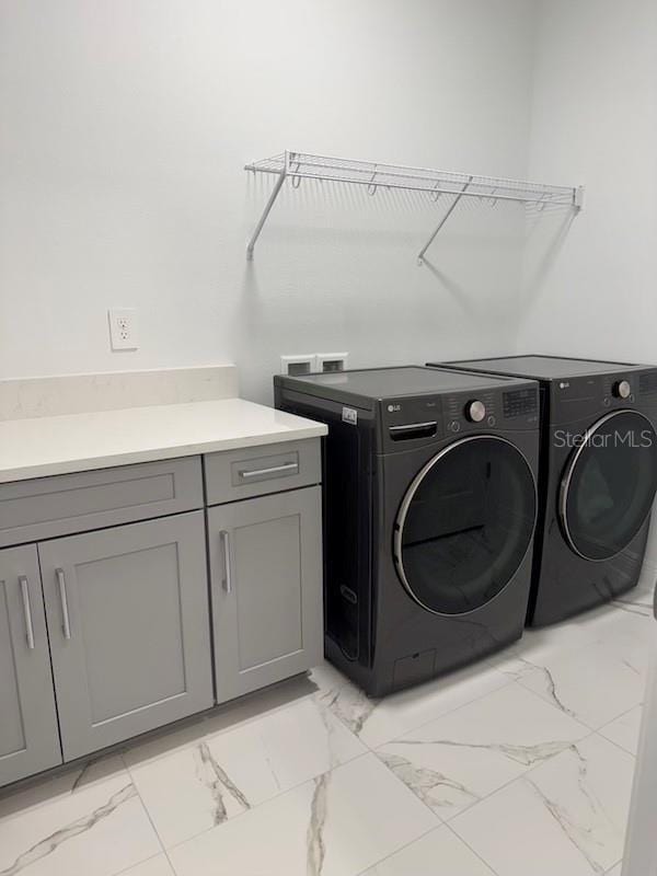 laundry room with cabinet space, marble finish floor, and washing machine and clothes dryer