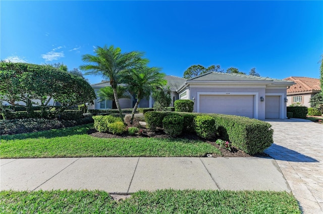 view of front of home featuring a tiled roof, decorative driveway, a garage, and stucco siding