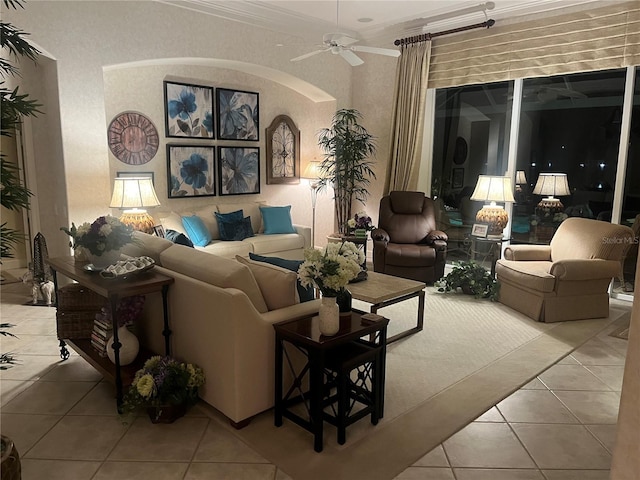 tiled living room featuring crown molding, a ceiling fan, and arched walkways