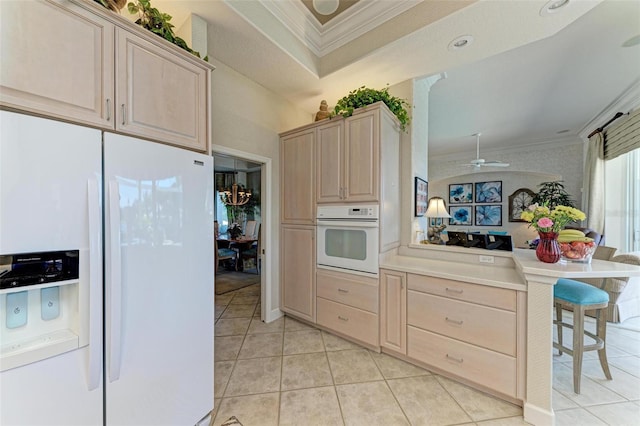 kitchen with light brown cabinetry, a ceiling fan, white appliances, a peninsula, and crown molding