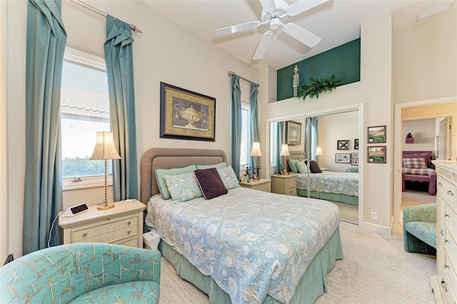 bedroom with light carpet, baseboards, a ceiling fan, and a closet