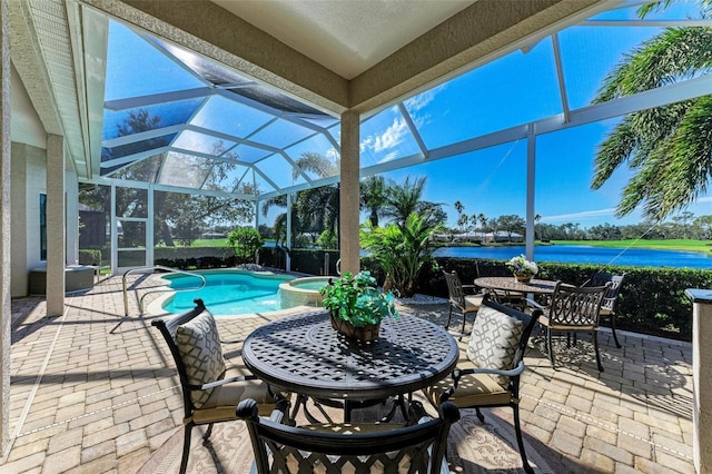 view of patio / terrace featuring glass enclosure, a water view, outdoor dining area, and a pool with connected hot tub