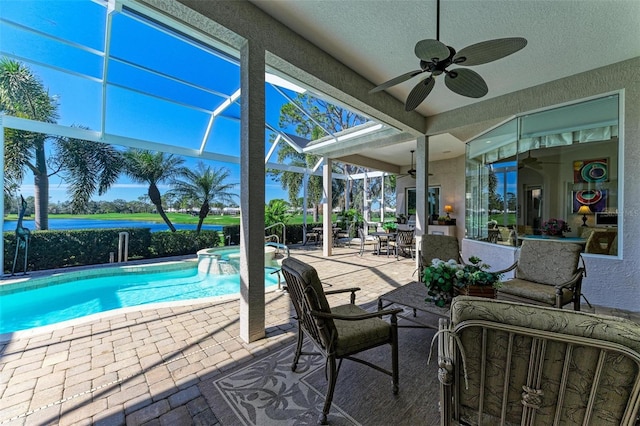 view of swimming pool with glass enclosure, a pool with connected hot tub, a ceiling fan, and a patio area