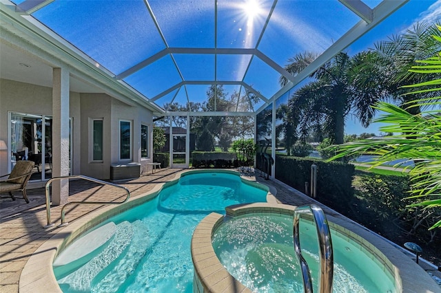 view of swimming pool featuring a patio area, a lanai, and a pool with connected hot tub