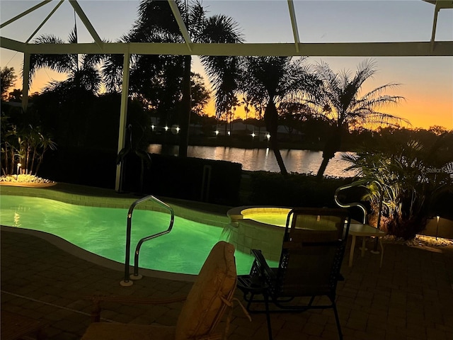 view of swimming pool featuring a lanai, a patio area, and a water view