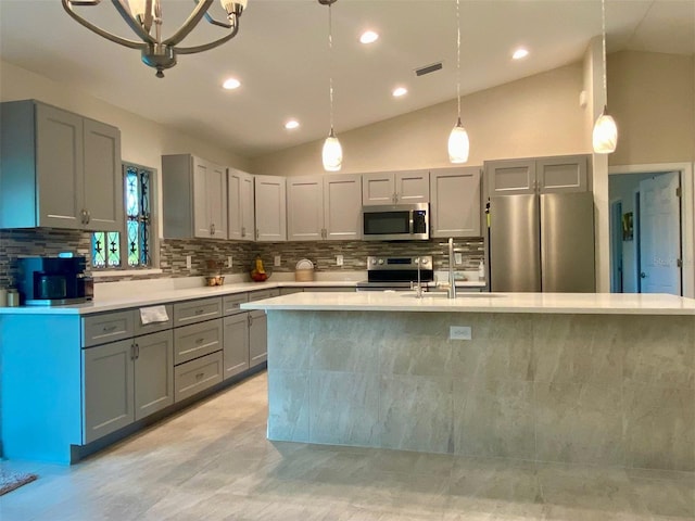 kitchen featuring tasteful backsplash, gray cabinetry, light countertops, stainless steel appliances, and a sink