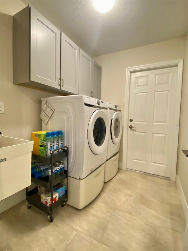 laundry room featuring cabinet space, separate washer and dryer, and a sink