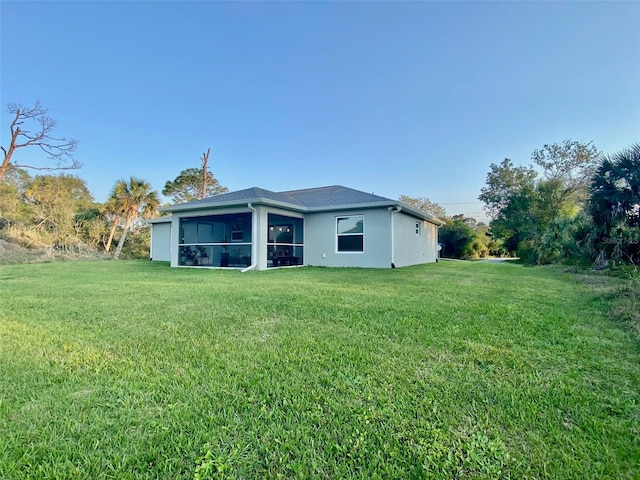 back of property featuring a yard, stucco siding, and a sunroom