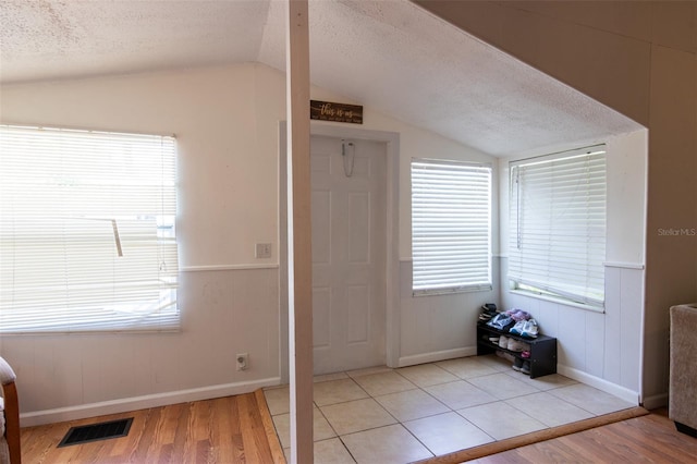 entrance foyer with visible vents, a textured ceiling, and vaulted ceiling