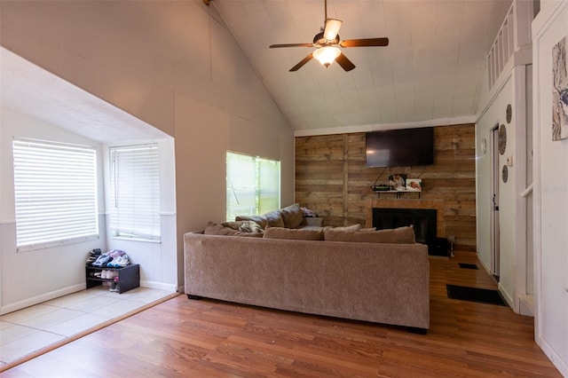 living room with vaulted ceiling, a fireplace, wooden walls, and wood finished floors