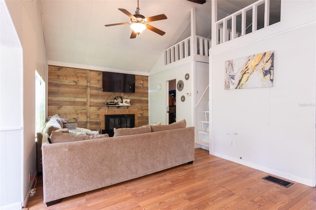 living area featuring visible vents, wood finished floors, a large fireplace, ceiling fan, and stairs