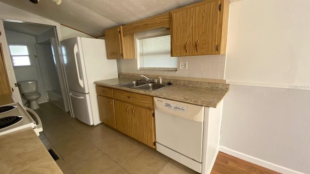 kitchen with white appliances, a sink, light countertops, vaulted ceiling, and backsplash