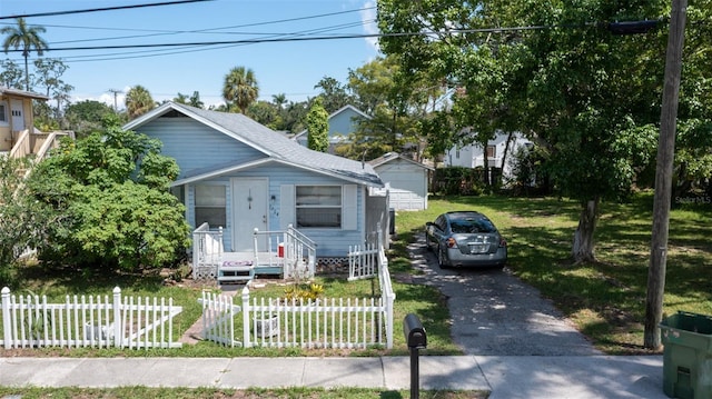 view of front of home featuring aphalt driveway, a shingled roof, a front yard, and fence