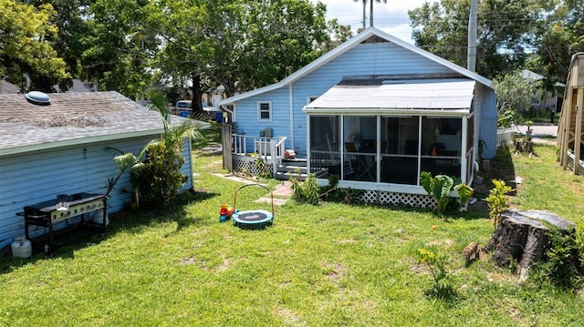 rear view of house featuring a lawn, roof with shingles, and a sunroom