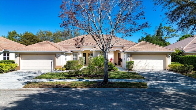 mediterranean / spanish house featuring a garage, concrete driveway, and a tiled roof