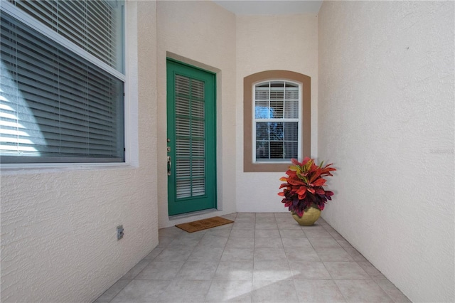 view of exterior entry featuring stucco siding and a patio