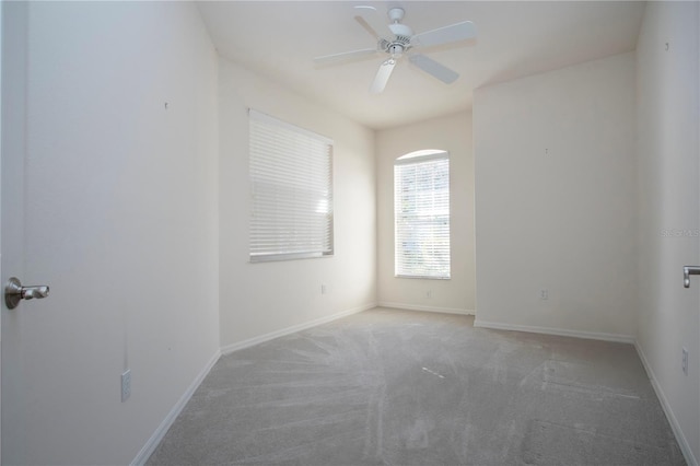 carpeted empty room featuring baseboards and ceiling fan