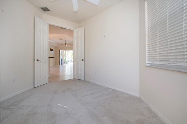 tiled empty room featuring baseboards, visible vents, carpet floors, and ceiling fan