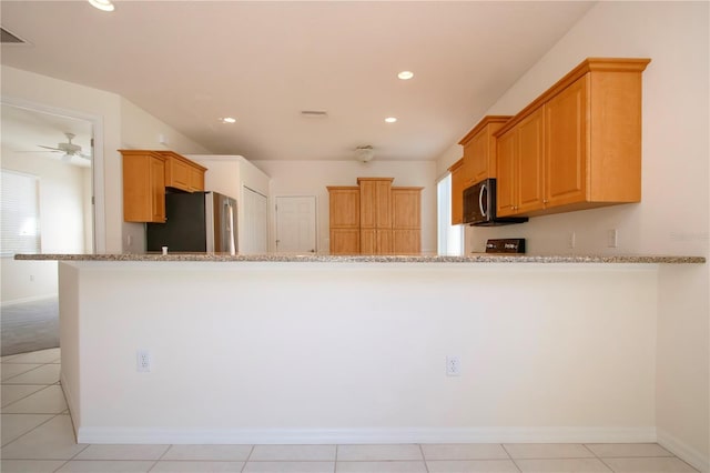 kitchen featuring light stone counters, stainless steel appliances, and recessed lighting