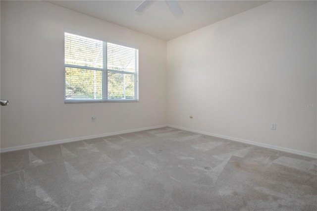 empty room with light colored carpet, baseboards, and ceiling fan