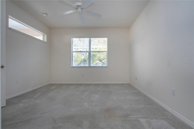 carpeted spare room with a ceiling fan and baseboards