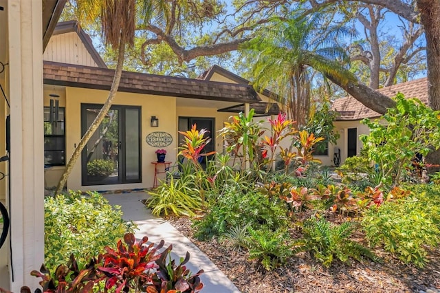 property entrance with stucco siding and roof with shingles