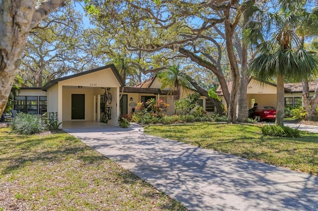 view of front facade with a carport, concrete driveway, and a front lawn