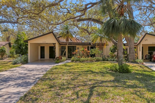 view of front of home featuring stucco siding, concrete driveway, a front lawn, and an attached carport