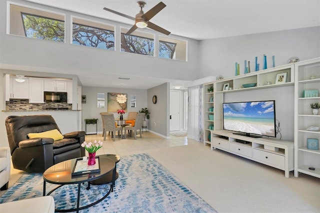 living room featuring baseboards, a high ceiling, and ceiling fan