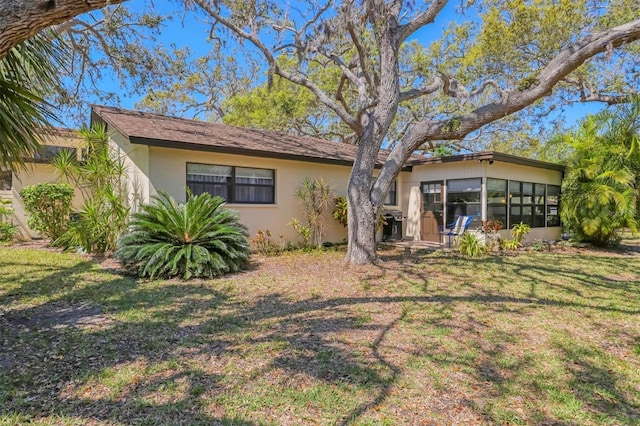 back of property with stucco siding and a lawn