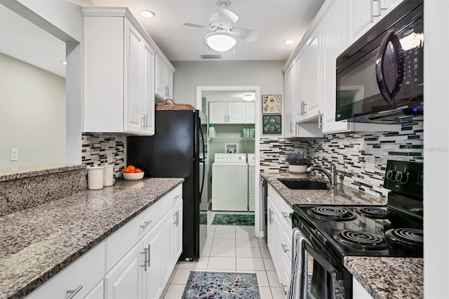 kitchen featuring visible vents, washing machine and dryer, white cabinets, black appliances, and a sink