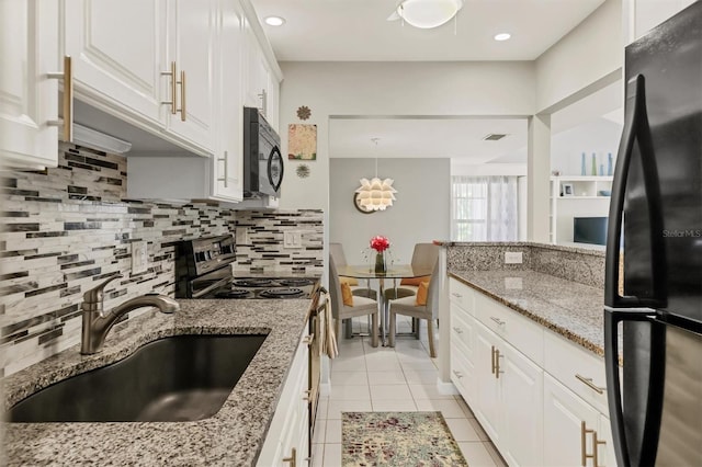 kitchen featuring black appliances, light tile patterned floors, decorative backsplash, white cabinetry, and a sink