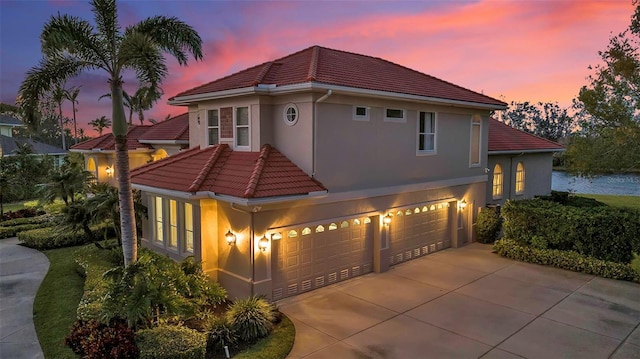 mediterranean / spanish-style home featuring stucco siding, concrete driveway, a tile roof, and a garage