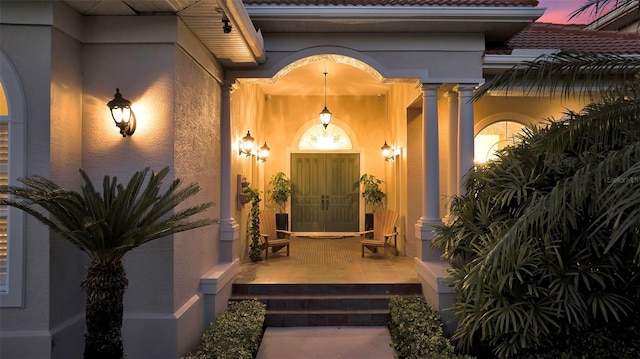 property entrance with stucco siding, a porch, and a tile roof