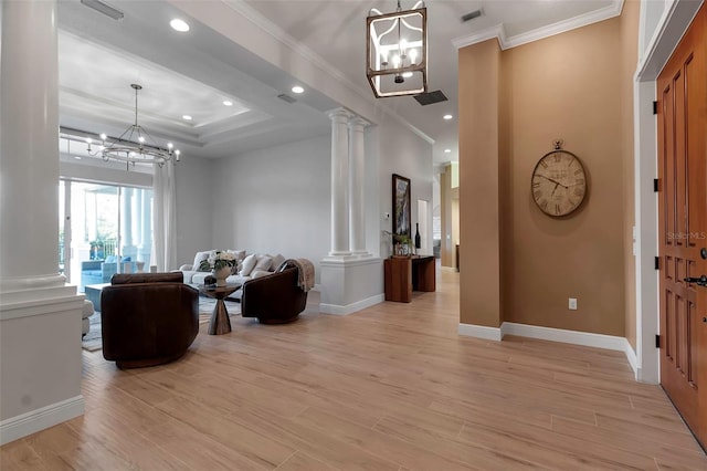 interior space featuring an inviting chandelier, crown molding, light wood-style floors, and ornate columns