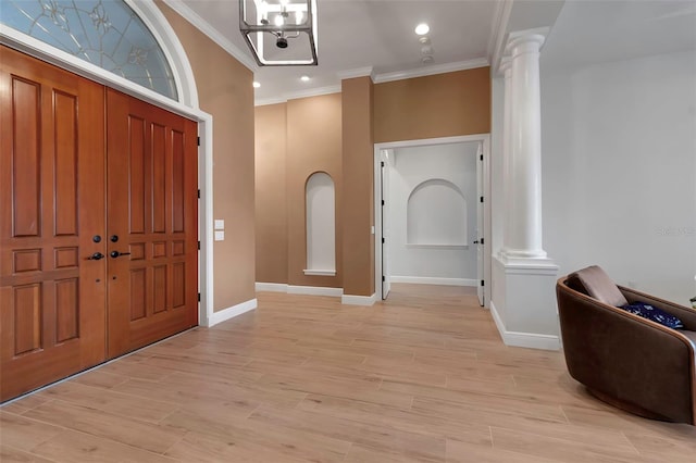 entryway featuring light wood-style floors, ornate columns, and ornamental molding