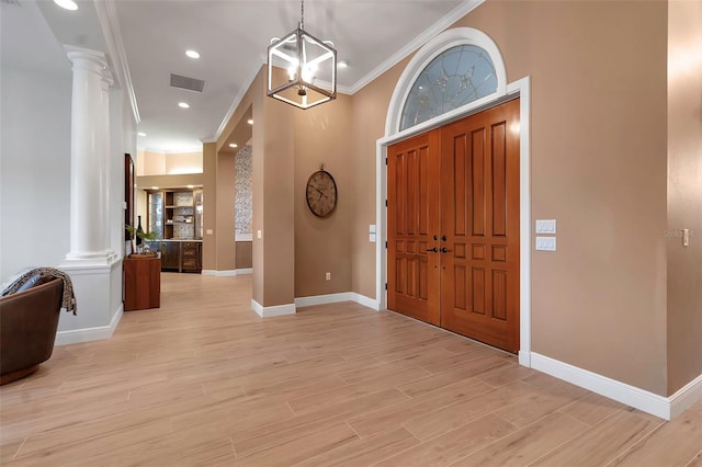 foyer featuring visible vents, crown molding, baseboards, decorative columns, and light wood-style flooring