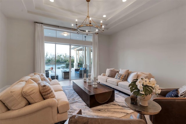 living room featuring a notable chandelier, recessed lighting, and a tray ceiling