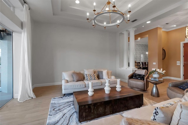 living area with visible vents, baseboards, a tray ceiling, decorative columns, and light wood-style floors