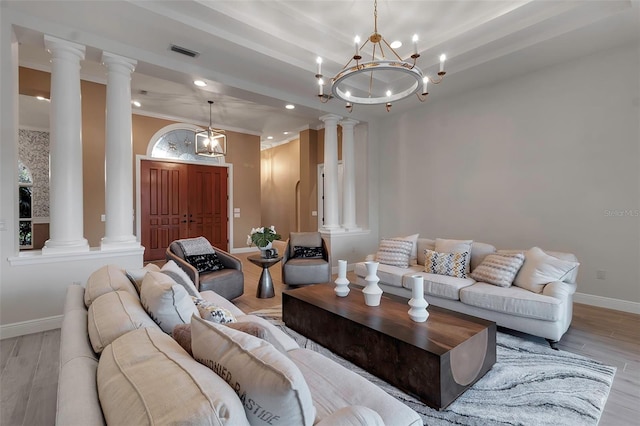 living room featuring wood finished floors, visible vents, ornate columns, and baseboards