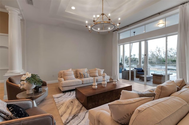 living room with baseboards, ornate columns, visible vents, an inviting chandelier, and light wood-type flooring